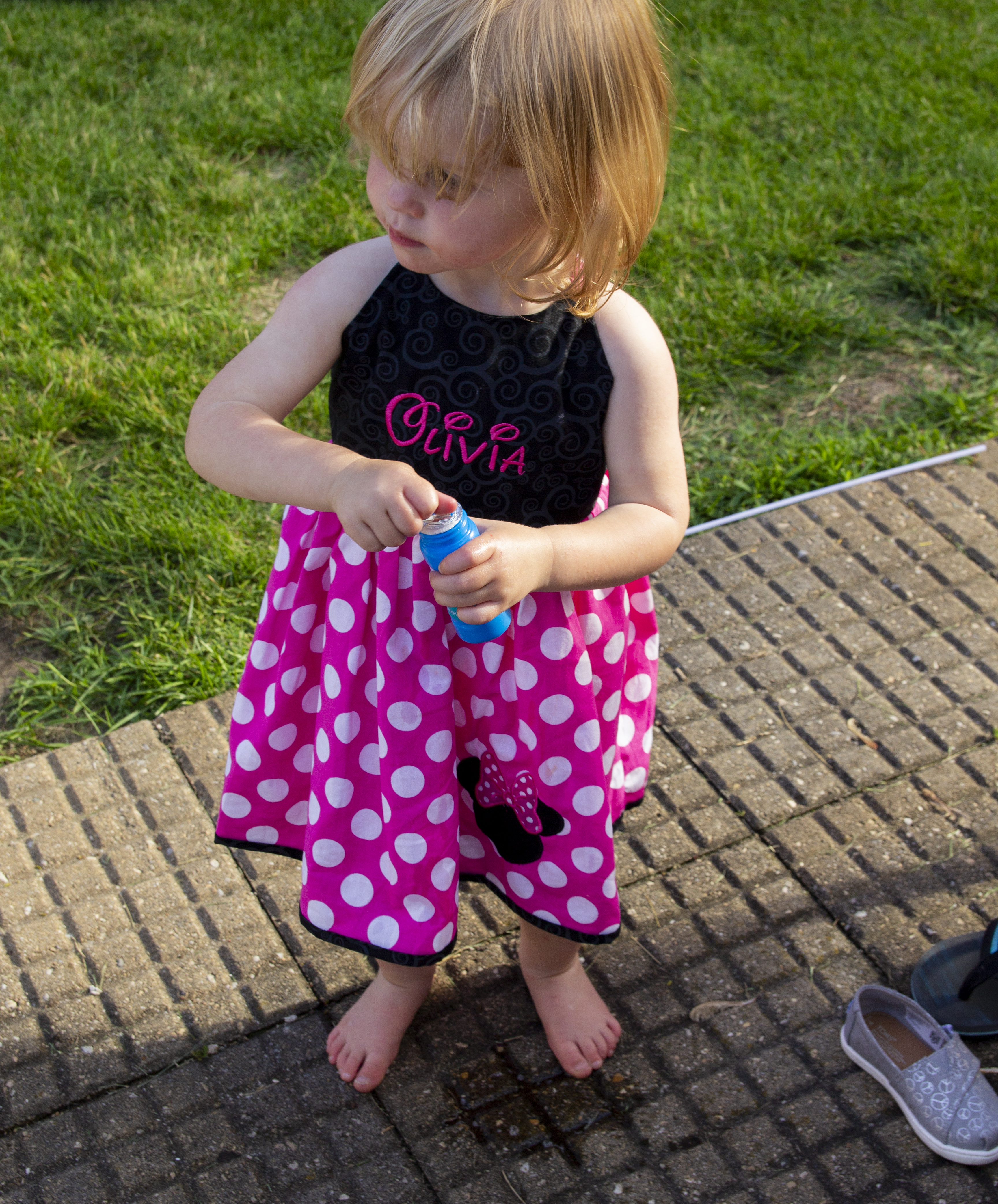 Two year old opening bubbles in her minnie mouse dress during a birthday party