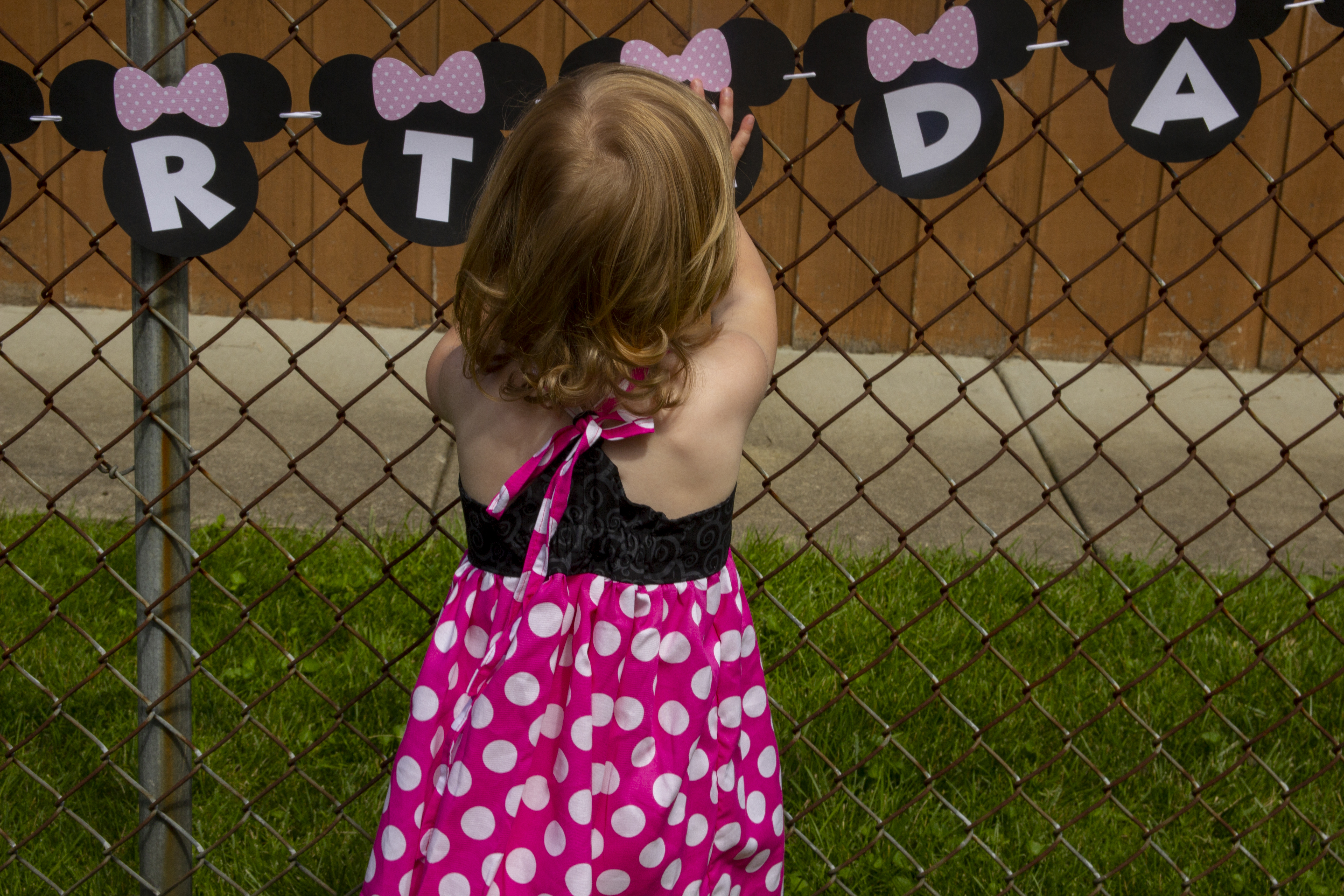 Back detail of a two year old wearing a minnie mouse dress during her birthday party