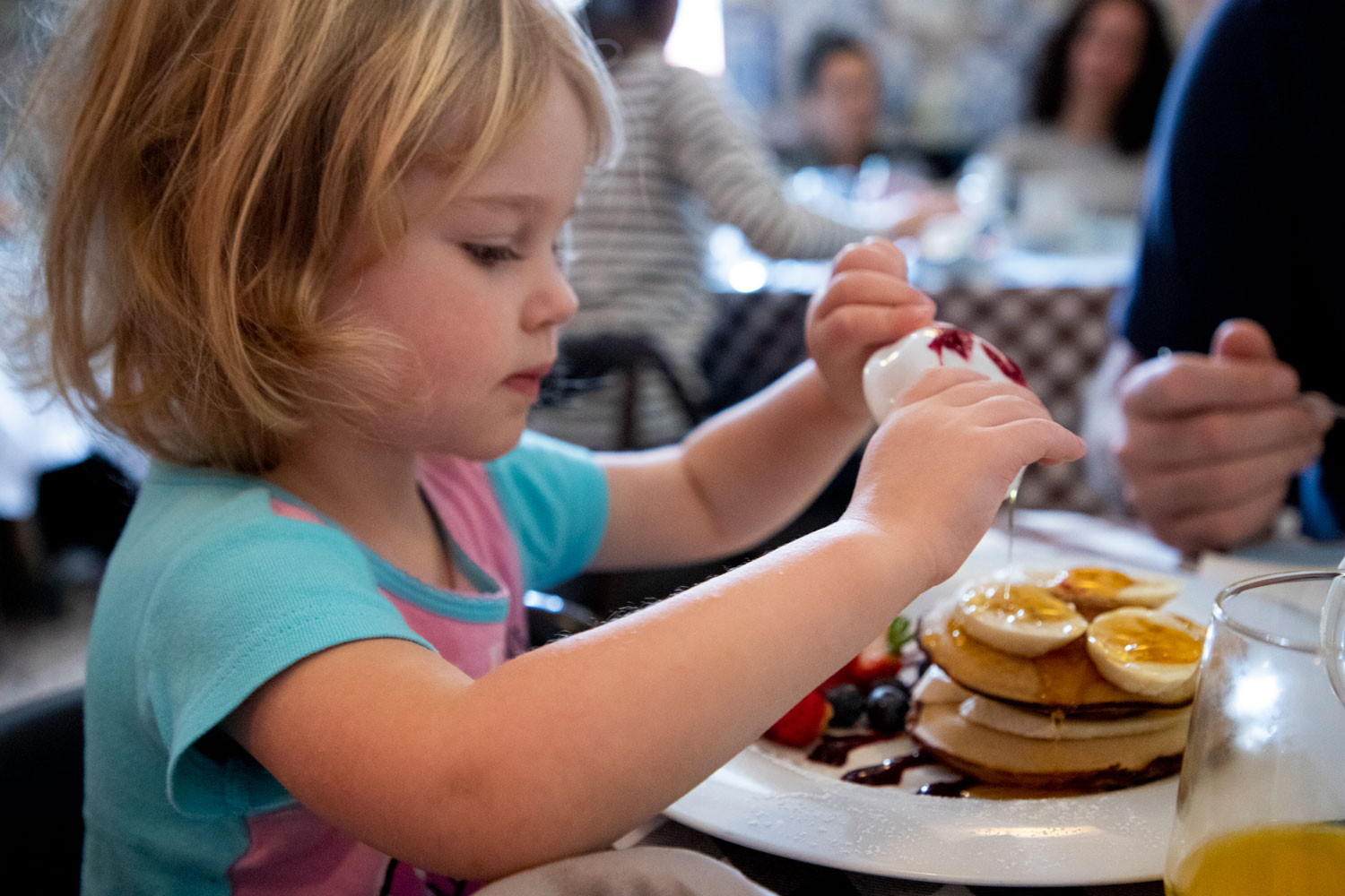 3 year old puts syrup on pancakes during breakfast | Lisbon with kids