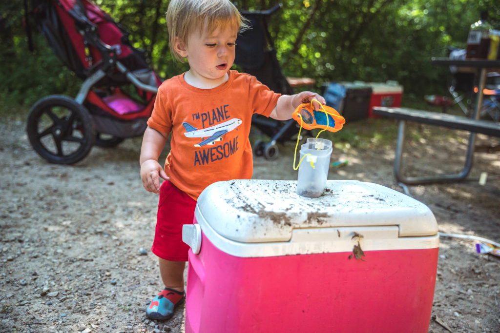 1-year old using a bug catcher while camping