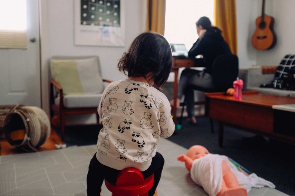 woman works from home with toddler playing