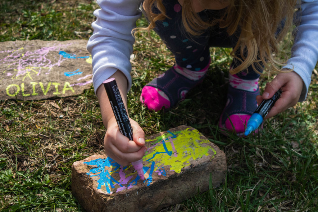 Toddler painting rocks outside