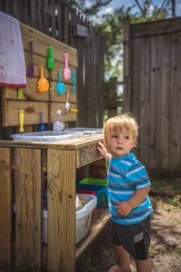 toddler boys plays with his homemade wood kitchen