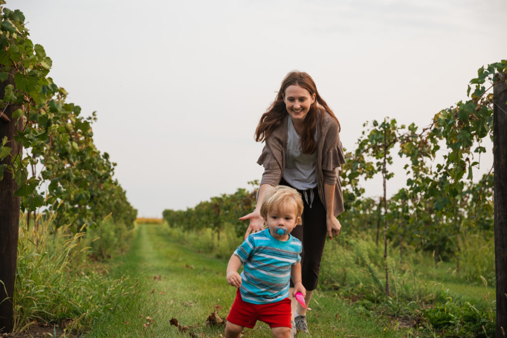 Mom and one year old son running through Vineyards during a Harvest Host stay at Wooden Wheel Vineyards in Iowa