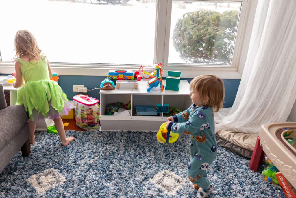 4-year-old and 1-year old helping to pick up toys during family clean up time