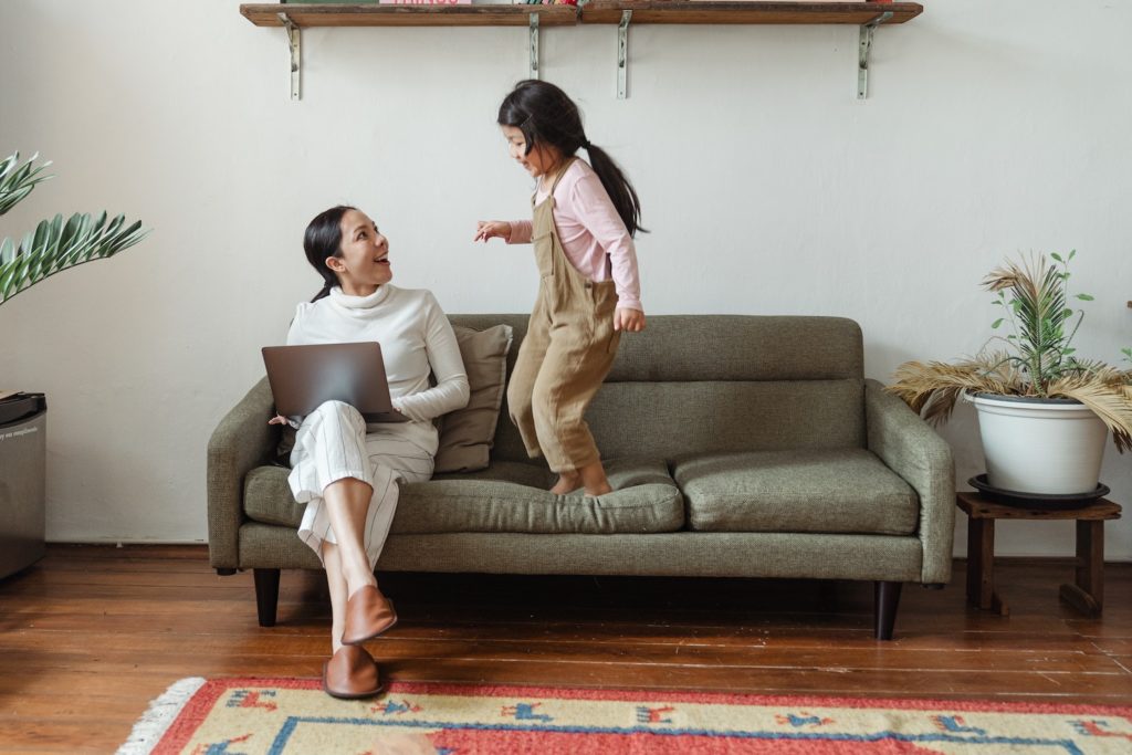 kid jumping and talking to mom while working