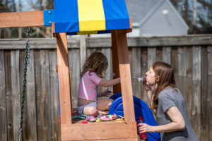 mom and daughter blowing bubbles outside