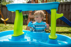 3 year old boy playing with a water table outside
