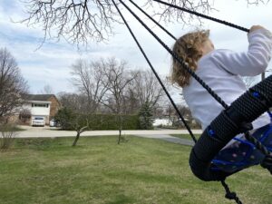 6 year old girl swinging on a tree swing outside